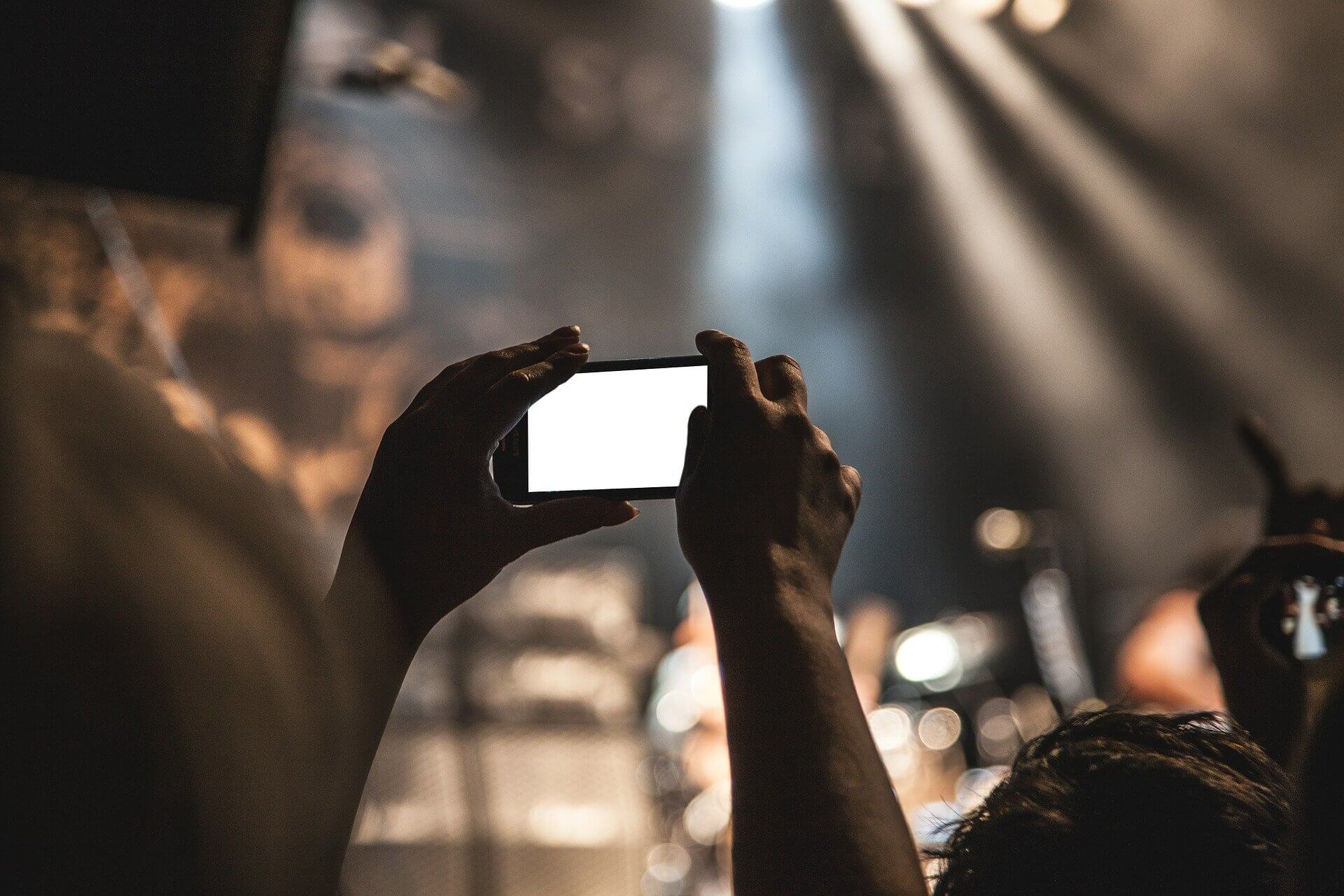 Hands holding a smartphone, recording an event