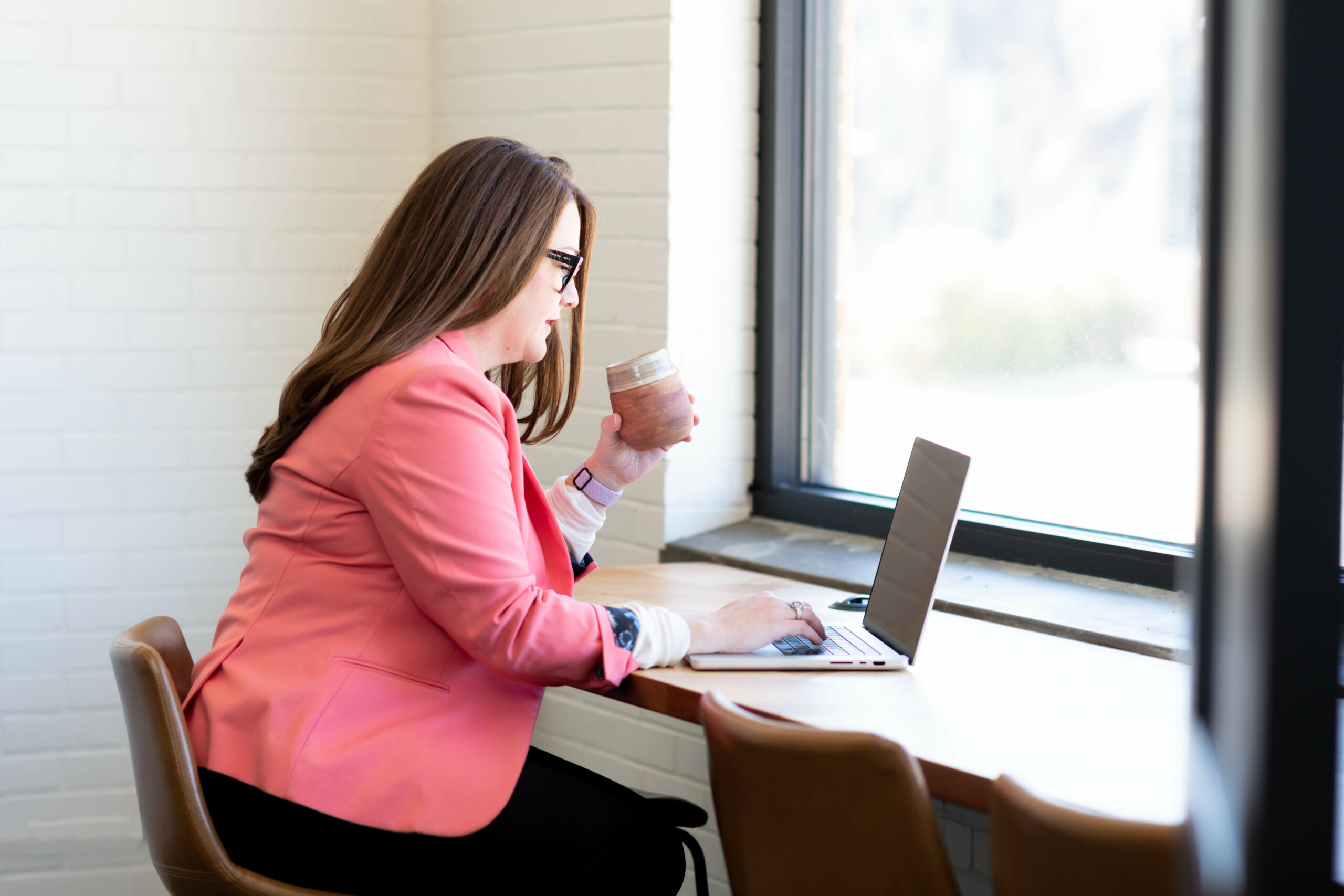 A woman, working at a laptop for clients who have outsourced content writing.