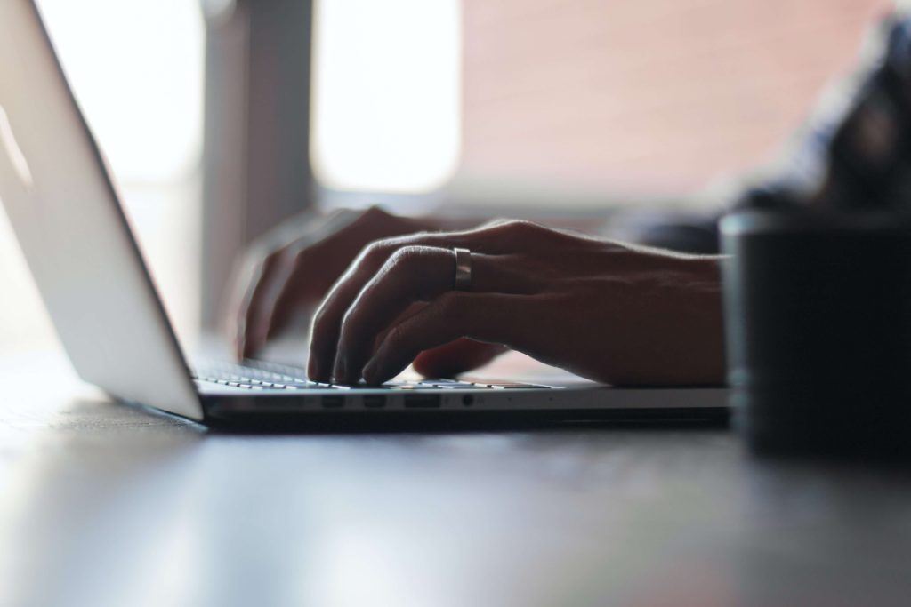 A close-up of a man's hands on a laptop keyboard