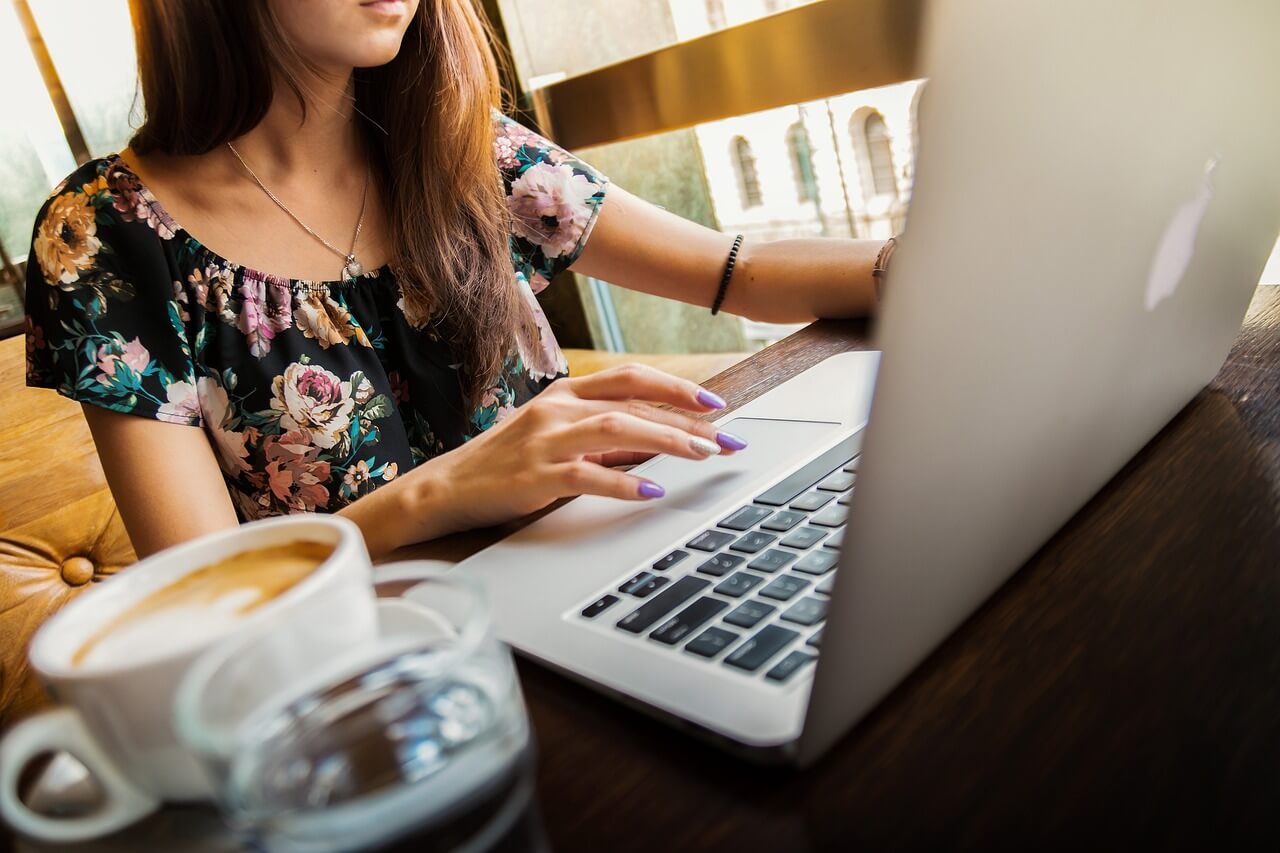 A woman working on a laptop with a cup of coffee nearby